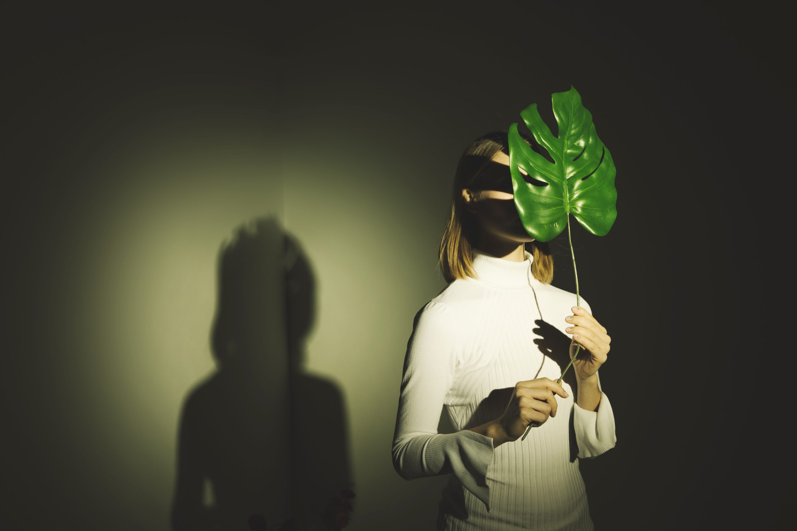 woman covering face with big green leaf scaled